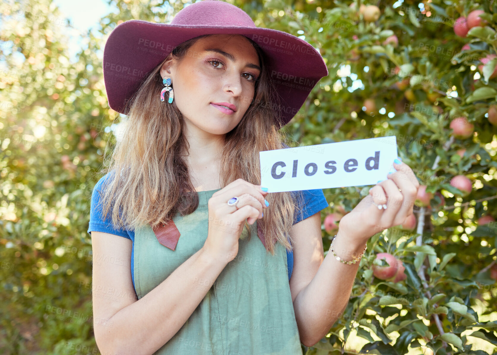 Buy stock photo Portrait of one woman holding closed sign to advertise the end of apple picking season on orchard farm. Farmer closing agriculture business due to bankruptcy, recession, pandemic and failed economy 