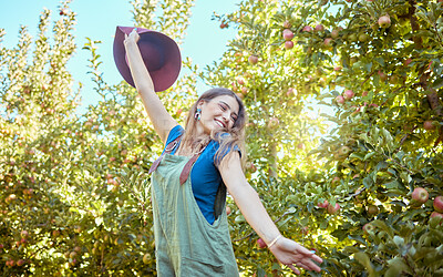 Buy stock photo Excited young woman jumping for joy in an apple orchard on a sunny day outside. Happy and cheerful farmer feeling optimistic, free and full of energy after a fruitful harvest on her successful farm