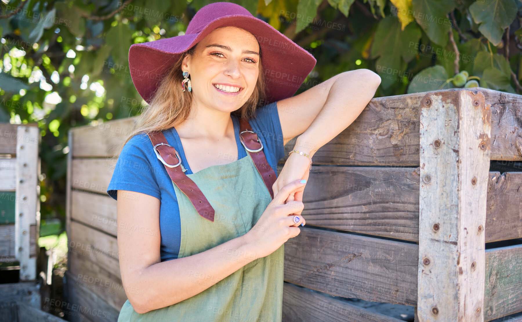 Buy stock photo Portrait of a happy woman on a farm. Young farmer on a organic, sustainable orchard on a sunny day. Female smiling  on peaceful farmland, leaning on a wooden crate after picking apples in nature