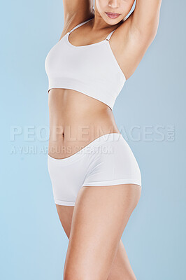 Close up of woman posing in white underwear and against a blue studio background. Fit, sporty model standing alone, isolated and showing her perfect body. Take care of your body and health