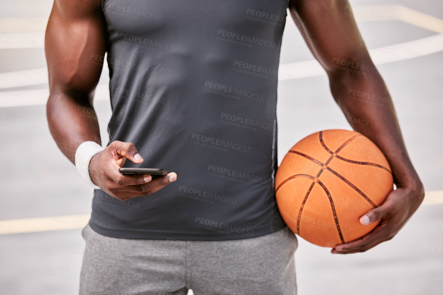 Buy stock photo Closeup of a basketball player texting on a phone while taking a break from playing a match on a sports court outside. Hands of one male athlete browsing social media online during a game interval