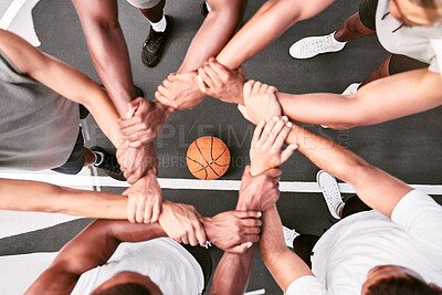 Group of sporty men forming a circle by holding each others wrists while huddling during a basketball game. Basketball players joining hands in a huddle for support and unity from above