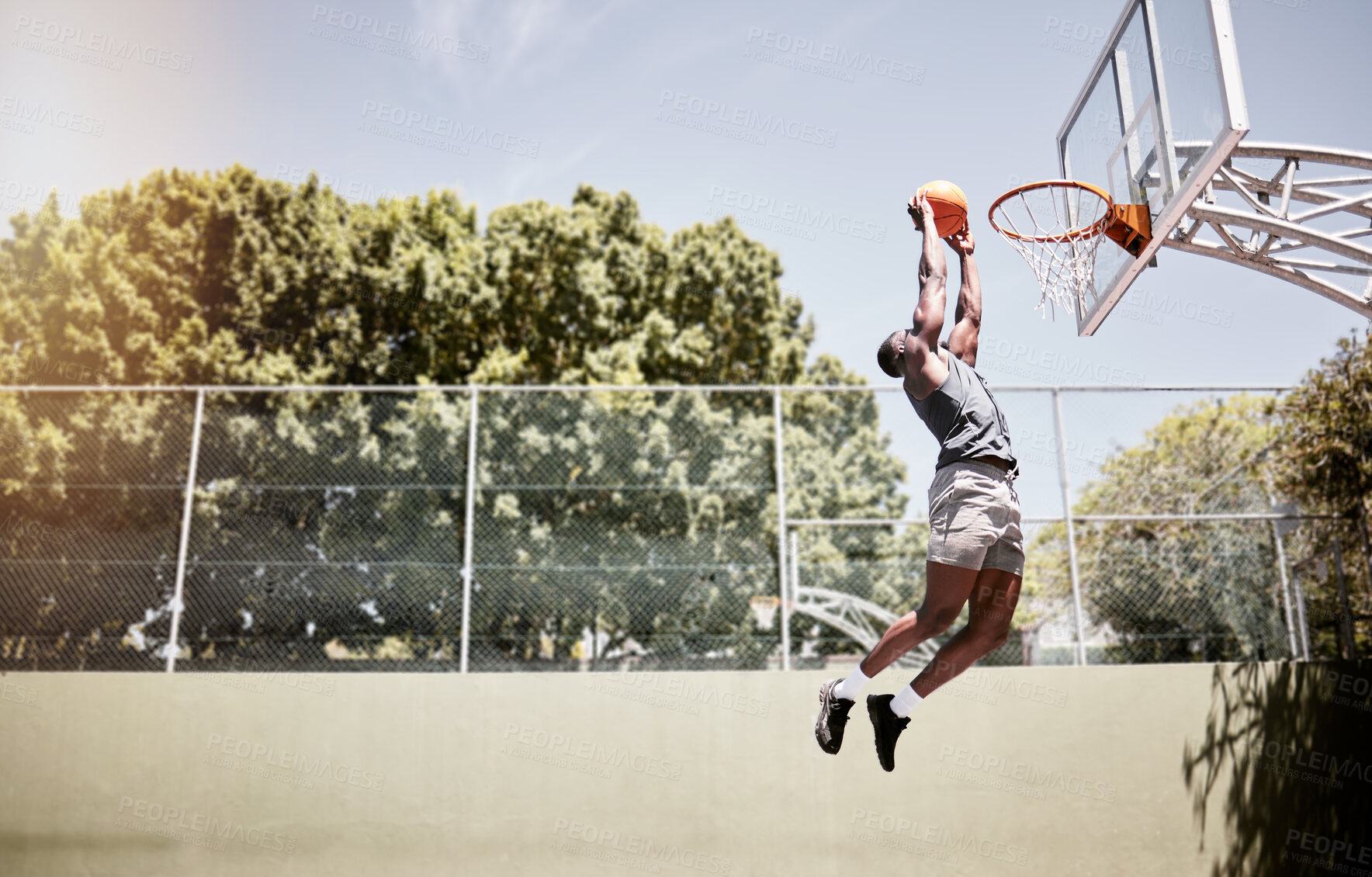 Buy stock photo Full length of basketball player dunking a ball into the net during a match on a court. Fit and active athlete jumping to score during a competitive game. Healthy athletic african man in action