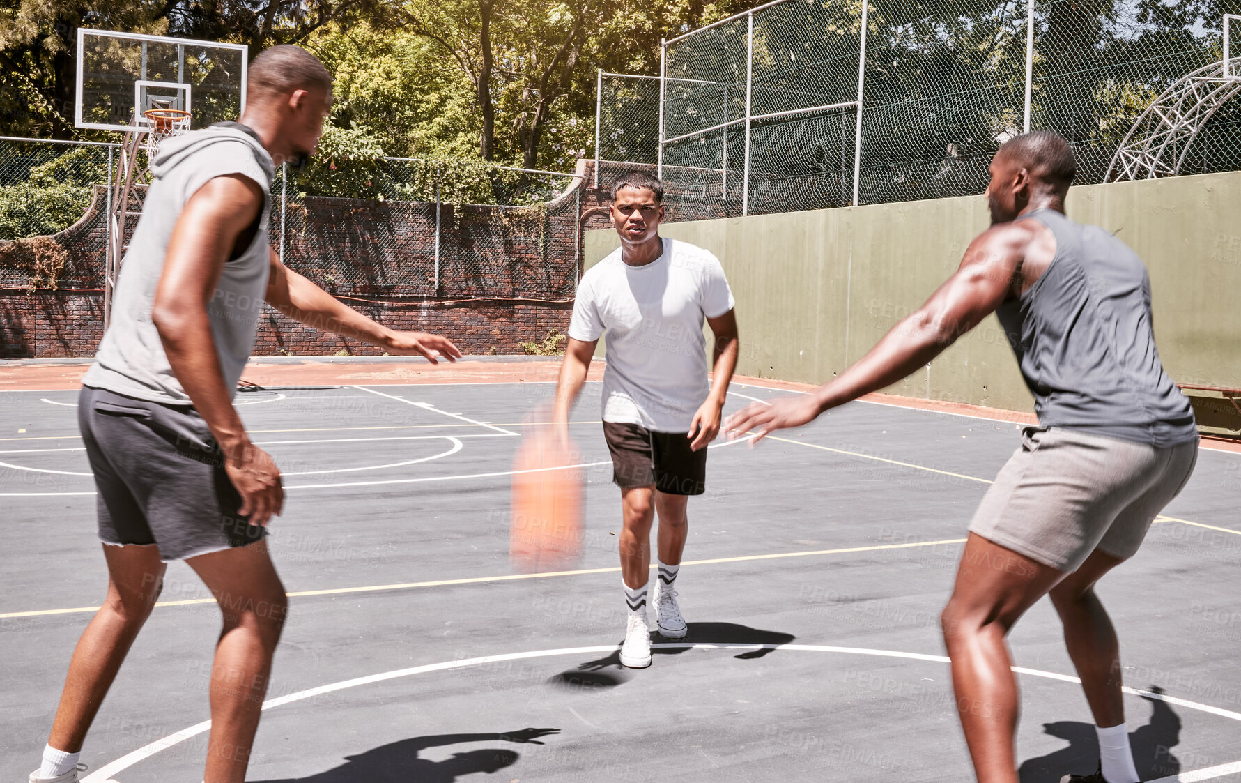 Buy stock photo Three african american men playing basketball on a court outdoors. Black man and his sporty friends being athletic outside. Group of basketball players competing in a match or game for recreation fun