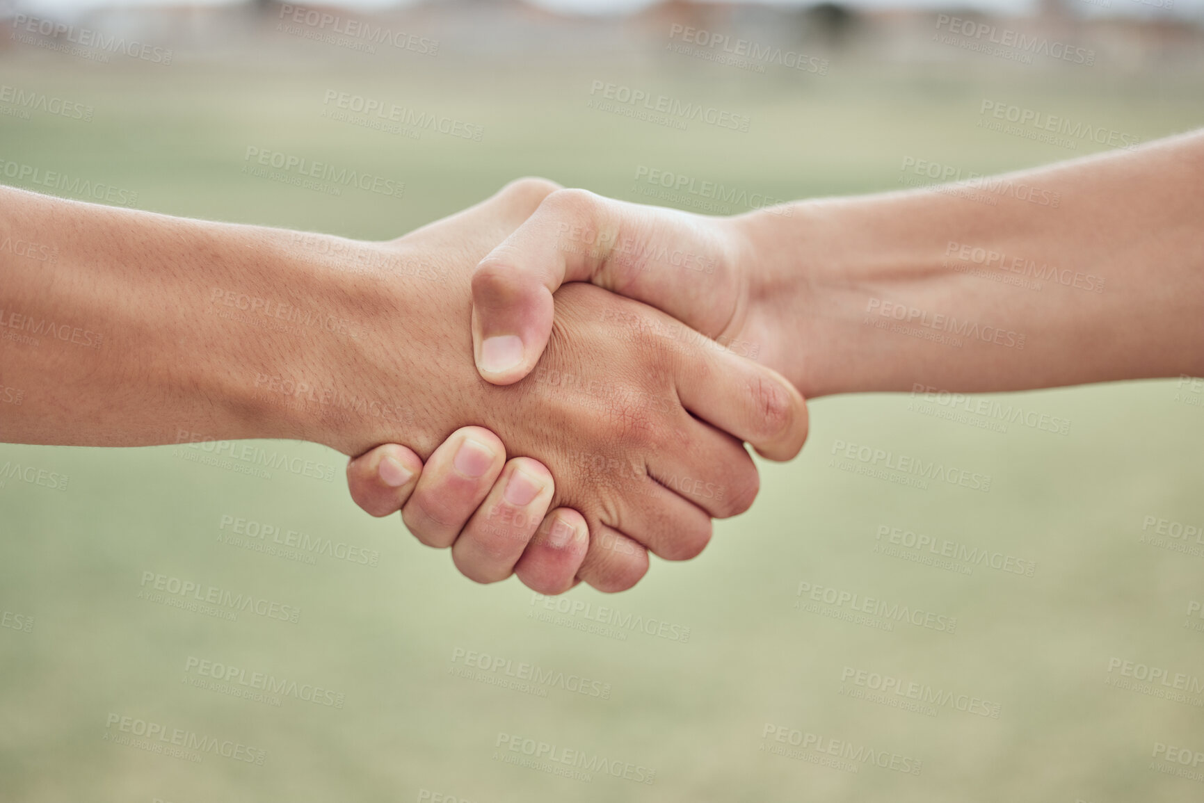 Buy stock photo Closeup of two unknown baseball players shaking hands while standing on a grass field. Two sportsmen greeting or congratulating on a good game