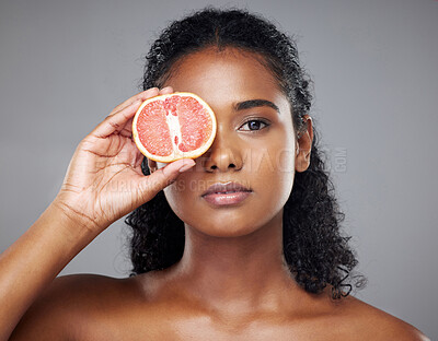 Buy stock photo Woman, face skincare or grapefruit for glow, relax wellness health or exfoliate facial on grey studio background. Portrait, Indian beauty model and vitamin c food product in hands for anti aging eyes