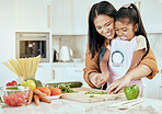 Happy, mother and child learning to cook with smile for help, guidance and support in the kitchen. Mama helping her little girl cut vegetables, food or meal for healthy diet and fun bonding at home