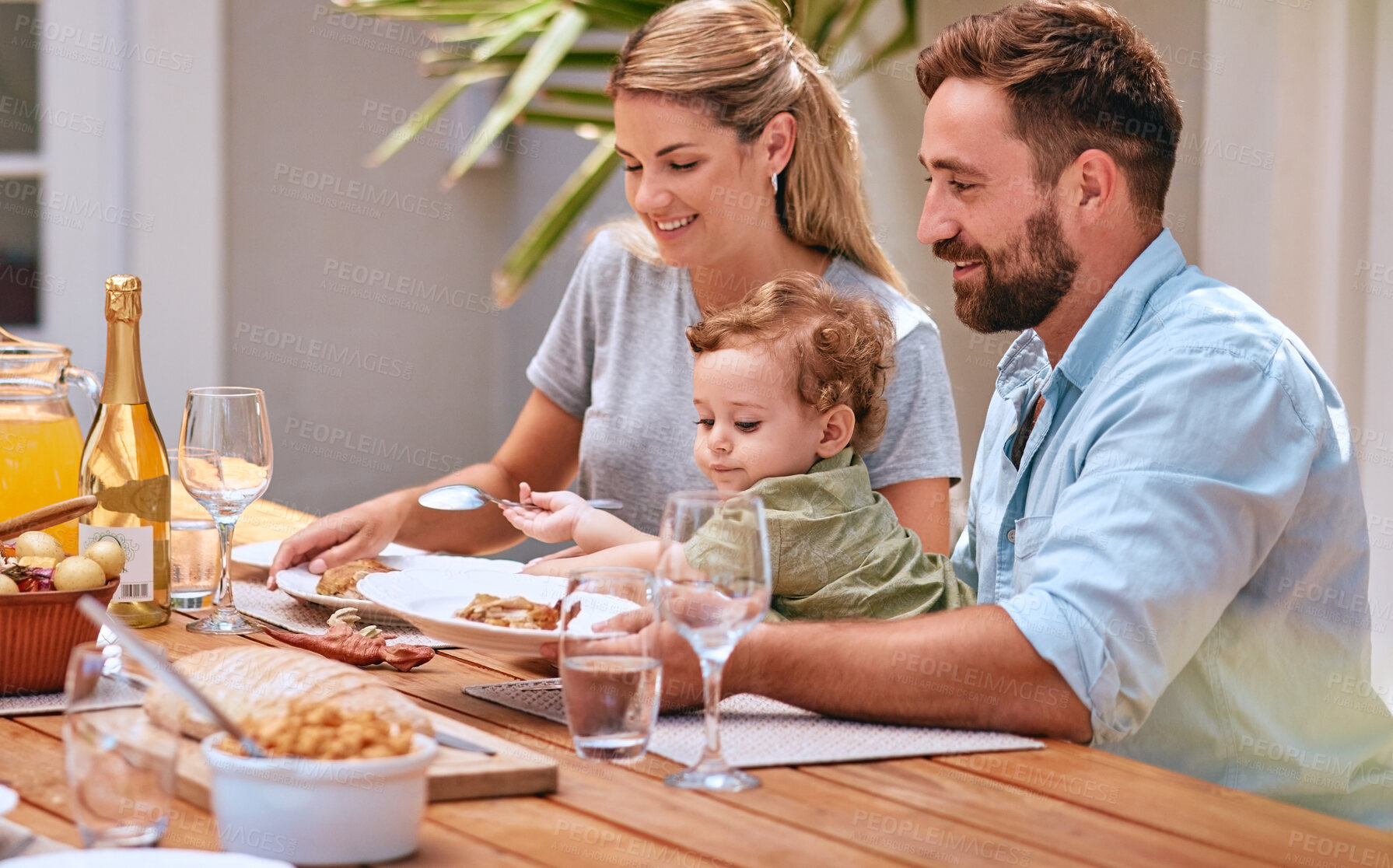 Buy stock photo Family, food and lunch outdoor with child, mom and dad together for meal, wine and bonding at patio dining table. Baby, man and woman happy while eating outdoor in summer for healthy lifestyle