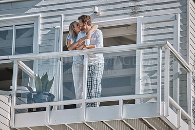 Buy stock photo Love, kiss and couple on balcony with coffee, espresso or cappuccino in home. Tea, relax and romantic man and woman enjoying quality time together, bonding or affection with view on holiday in house.