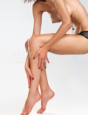 Buy stock photo Nude woman rubbing lotion onto her leg with care, isolated on a white background
 - copyspace