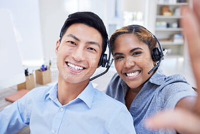Happy and diverse call center agents or colleagues taking a selfie together at the office. Male and female customer service coworkers take a picture or photo smiling in the workplace