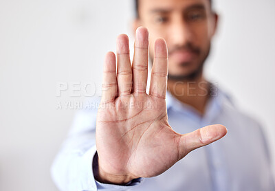 Closeup of the hand of a business man showing stop, saying no or not accepting a deal in an office at work. Male corporate worker making hand gesture not agreeing to a statement or refusing an answer