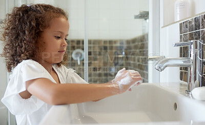 Buy stock photo Little girl washing hands with water and soap in bathroom at home. Learning about and practicing good hygiene  keeps us healthy. Child cleaning fingers at a basin or sink
