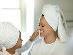 Cute mother and daughter applying lotion and doing a skincare routine together. Adorable little girl and mom doing a facial or having a self care day. Parent and child enjoying a skin cleanse at home