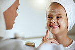 Cute, happy and little girl doing beauty treatment together with her mother. Daughter getting a facial and smiling in the bathroom at home. Adorable child copying her mom, bonding and smiling inside