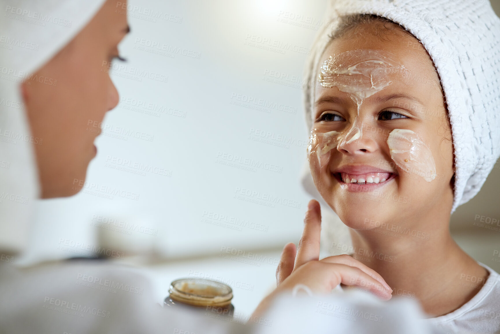 Buy stock photo Cute, happy and little girl doing beauty treatment together with her mother. Daughter getting a facial and smiling in the bathroom at home. Adorable child copying her mom, bonding and smiling inside