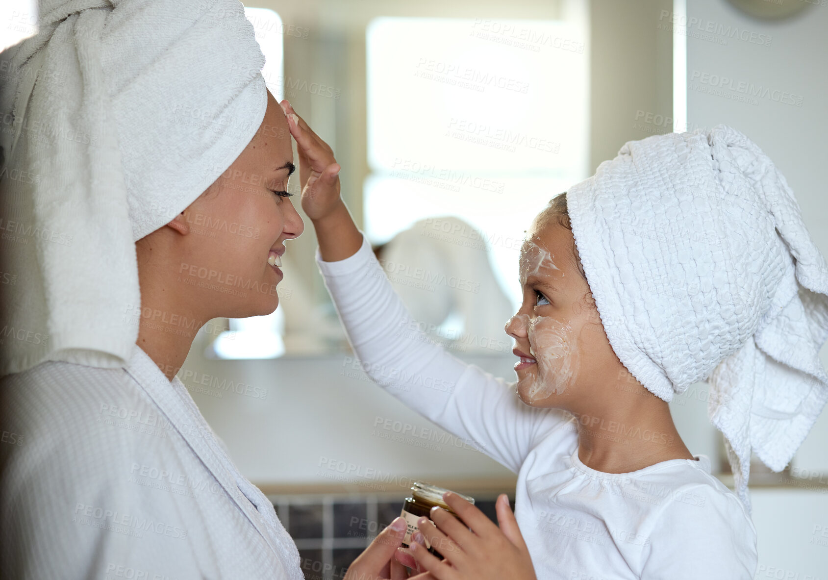 Buy stock photo Mother and daughter bonding and spending time together  on a spa day at the family home. Little girl applying face cream while smiling and having fun. Happy mom and child doing a skin facial