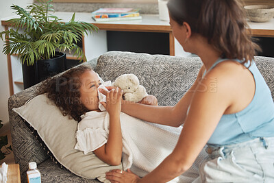Buy stock photo Caring, loving and worried parent taking care of ill kid. Suffering from cold, flu or covid virus. Daughter, child and sick girl lying on sofa while mother helps her blow her nose in home living room