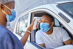 Drive thru for covid screening or testing service for people driving or traveling. Black man wearing a mask in a car getting his temperature test using an Infrared Thermometer as coronavirus protocol