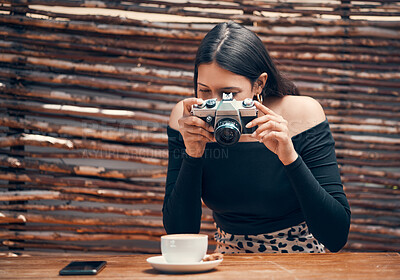 Buy stock photo Stylish, trendy and creative food influencer taking a picture with a camera of a cup of coffee for her blog in a cafe shop. Young female content creator taking a photo for her blog website at a cafe