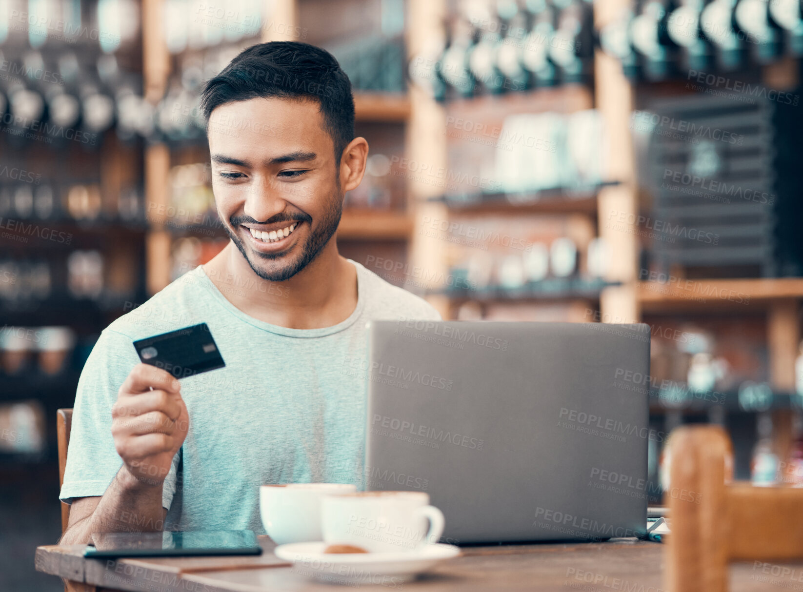 Buy stock photo Man doing online shopping, purchase or loan with credit card and laptop at an Internet cafe. Young happy male paying off insurance debt on a digital banking app with modern tech and looking satisfied