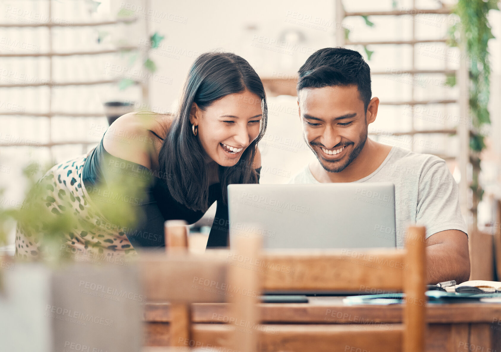 Buy stock photo Happy, laughing and casual couple watching or looking at a funny video on a laptop together in a restaurant during day time. Young boyfriend and girlfriend sharing relationship status on social media