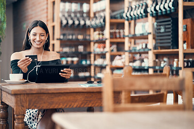 Buy stock photo Online shopping with a credit card at a cafe by a trendy woman browsing on a tablet with earphones and paying for her bill at a coffee shop. Happy woman enjoying a break and downloading a finance app