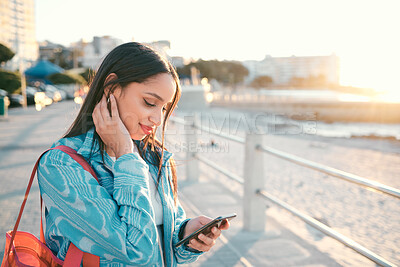 Buy stock photo Young, stylish and elegant woman browsing phone on a beautiful day. Peaceful, stressless and smiling female on a beach front with a scenic view. Calm lady feeling happy to be outside in the city.