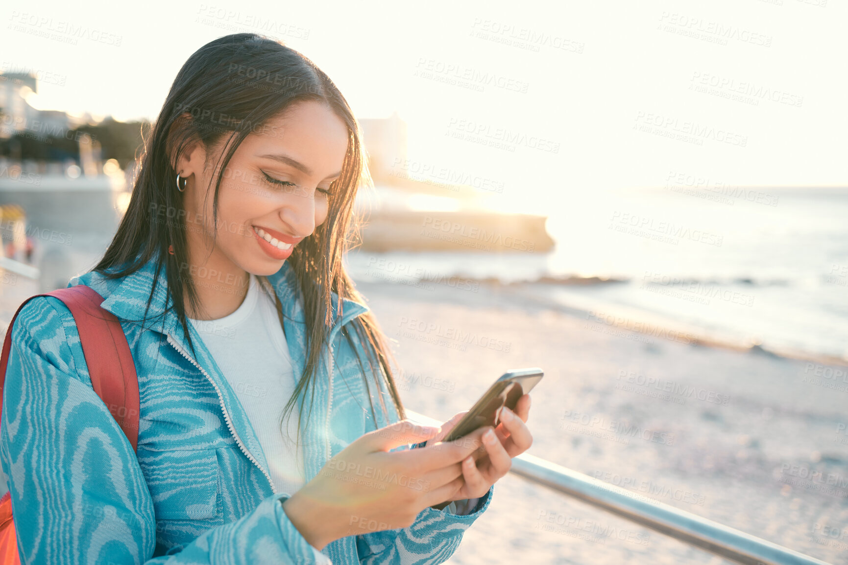 Buy stock photo Happy woman outdoors holding phone and texting, searching or sharing location on an online social media app. Single female enjoying the beach view and sharing experience on her tourism blogging site