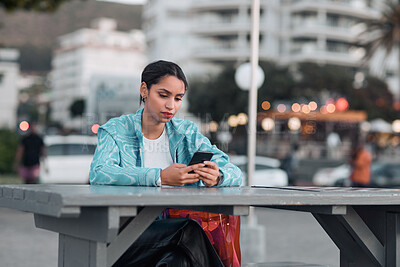 Buy stock photo Edgy, sad and lonely woman texting on social media dating app on a phone and looking serious, depressed or bored outside in an urban city. A single girl posting about her bad emotional breakup online