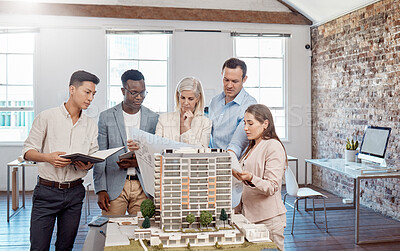 Buy stock photo A diverse team of architects working on a building model together inside the office. A group of engineers planning a reconstruction or design project of an apartment block with blueprint documents  
