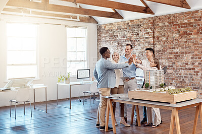 Buy stock photo Team of happy architect engineers celebrating together with a high five after completing a small apartment complex model to scale. Group of professional designers design a blueprint office building
