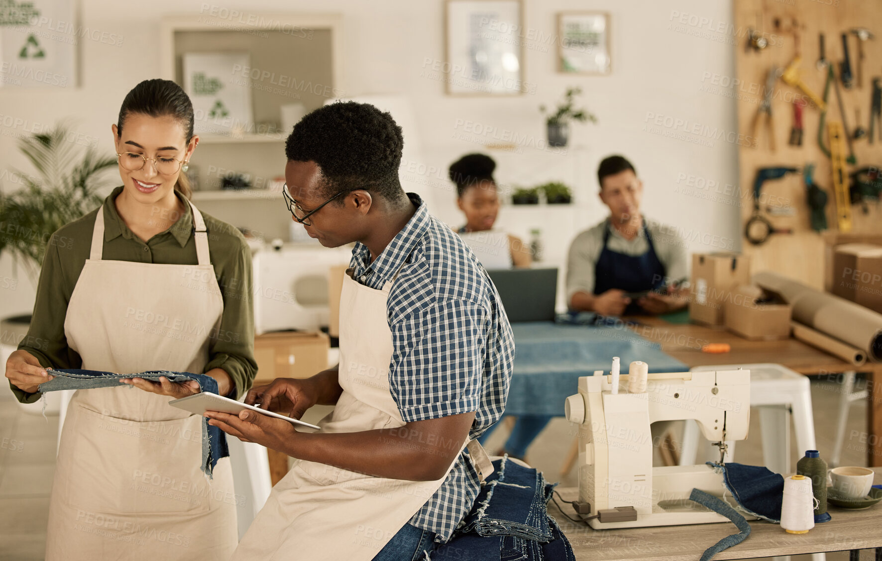 Buy stock photo Creative fashion designers learning sewing skills together on denim material in a manufacturing factory. Young man and woman design trendy new clothes with a sewing machine in a clothing workshop