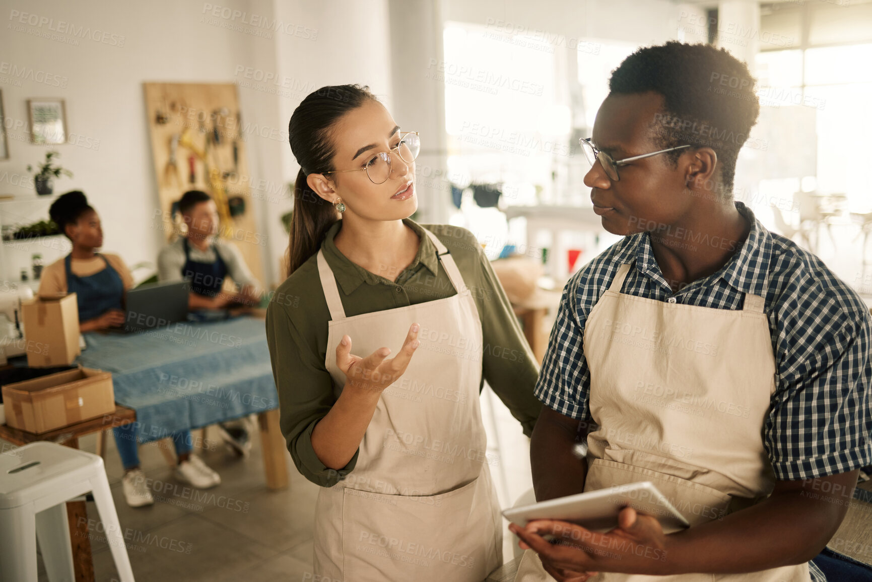 Buy stock photo Talking, planning and discussing tailors with a tablet designing new, trendy and stylish clothes. Design team colleagues asking or deciding a fashionable, funky style or cool fashion idea in workshop