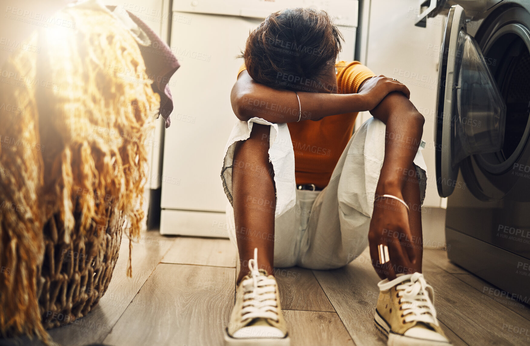 Buy stock photo Depressed, tired and stressed teen bored of doing household chores. African American young girl sitting doing the laundry with a headache. Annoyed at having responsibility, development