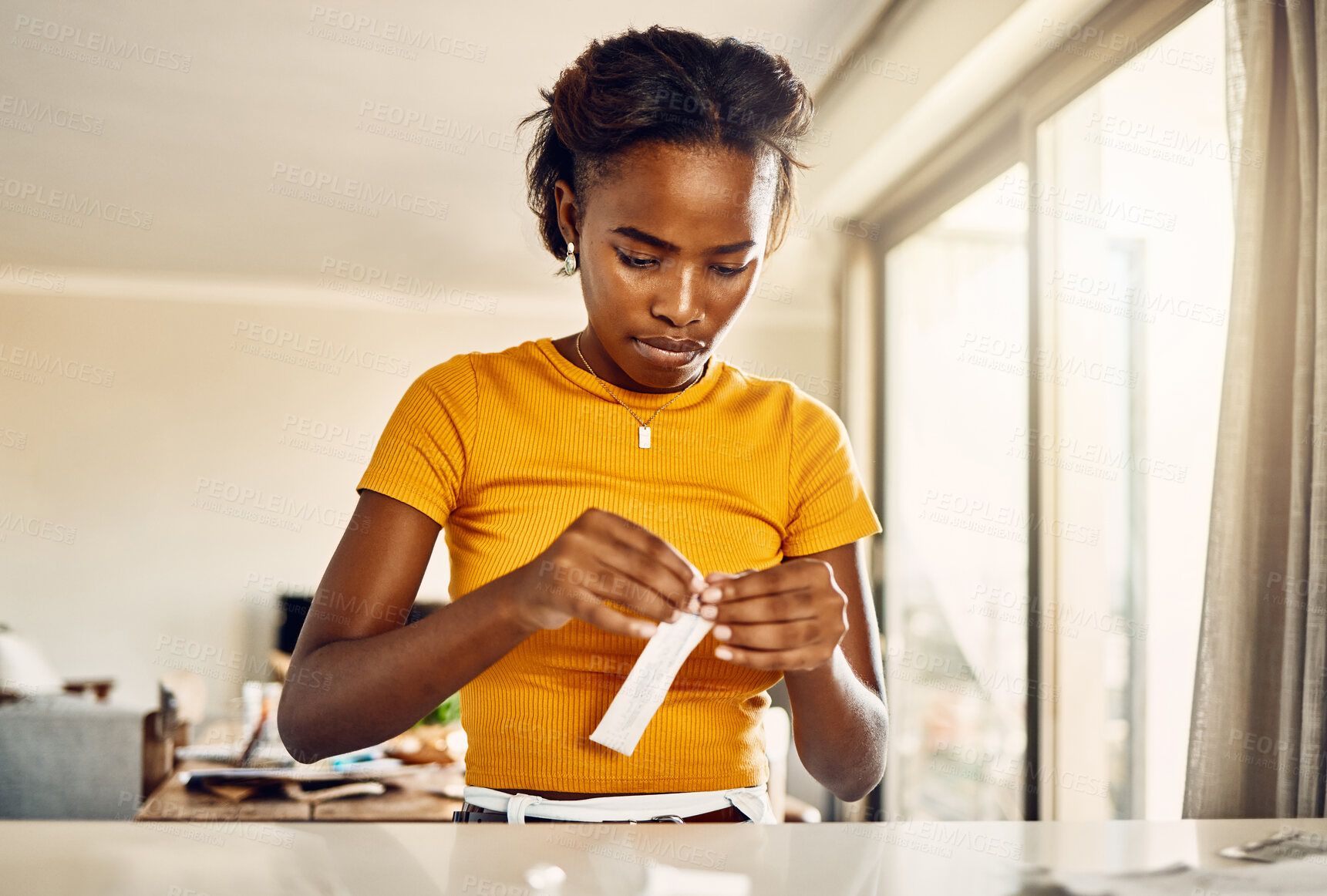 Buy stock photo Testing for covid or coronavirus with a rapid antigen test kit at home. African young woman opening a screening kit to diagnose a virus or infection during the pandemic from her house