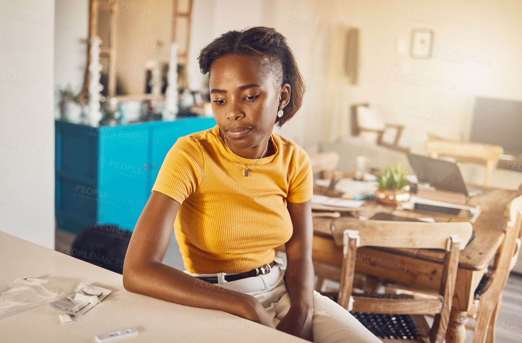 Buy stock photo A woman test for covid waiting for the results from the kit at home. Young casual African woman looking at her coronavirus or infection diagnosis from self testing equipment in her house