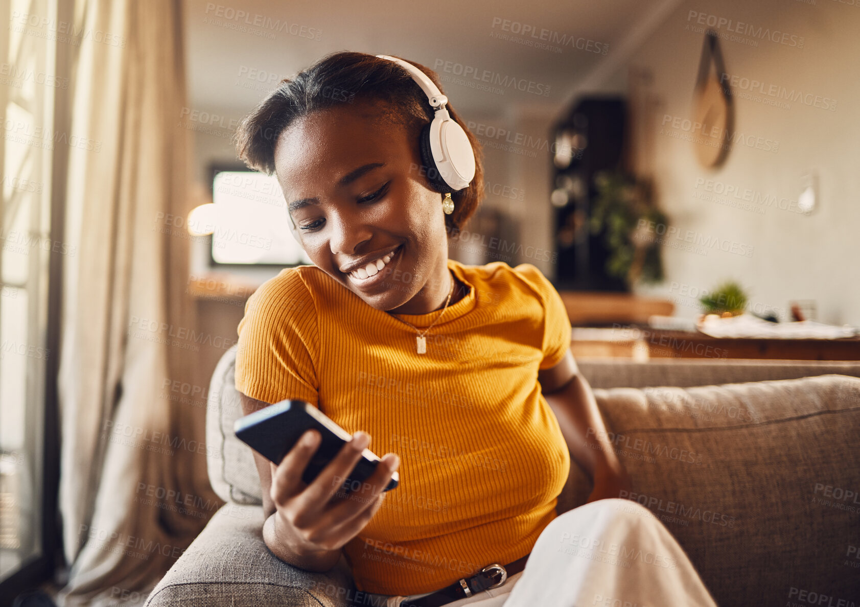 Buy stock photo Young woman texting, browsing and scrolling social media on a phone feeling happy, carefree and smiling. Listening to music, podcast or watching funny internet memes online while relaxing on a sofa