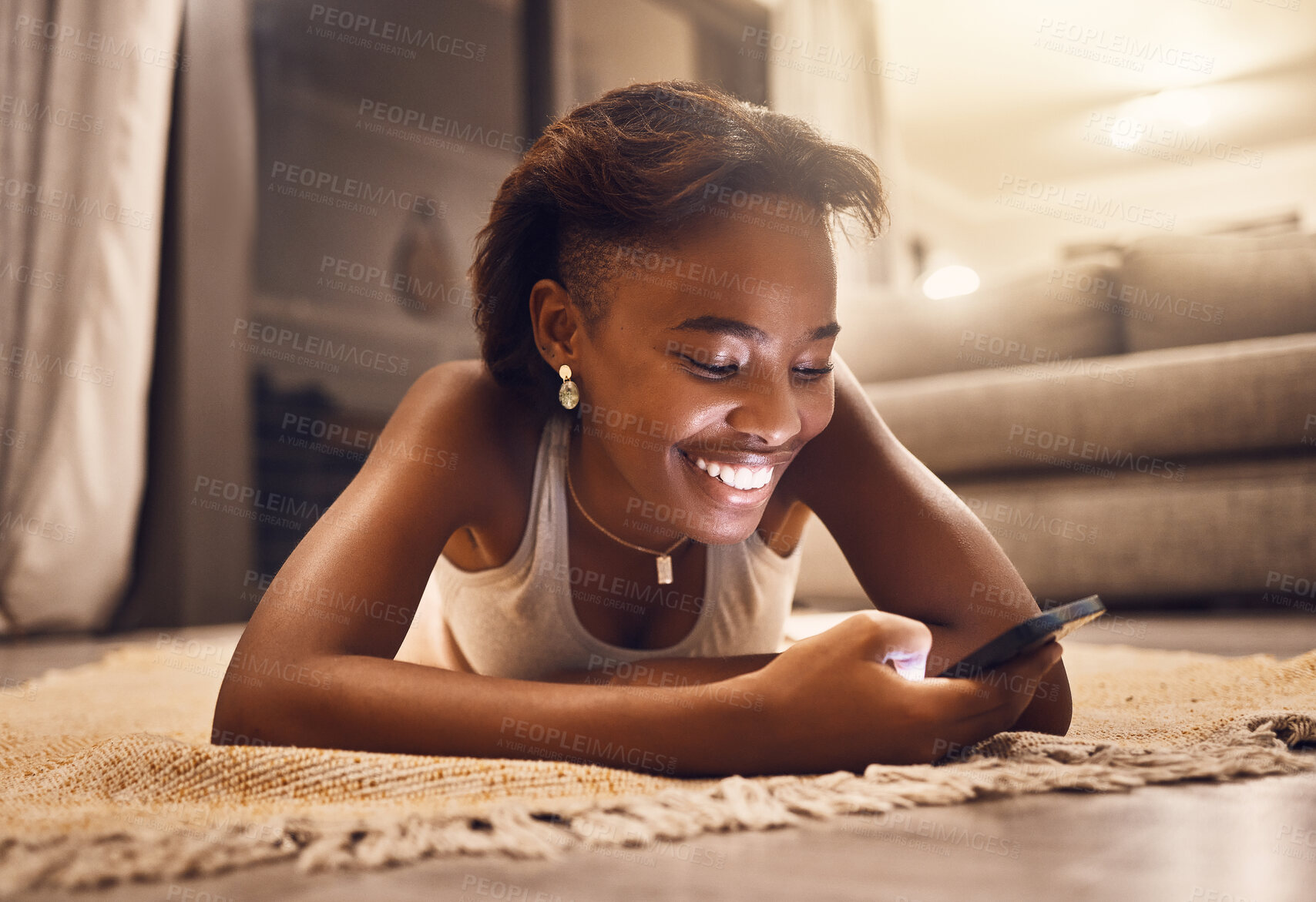 Buy stock photo Girl texting, chatting and checking social media on her phone while relaxing at home. Young woman browsing online app, enjoying rest and having fun being social on living room floor inside