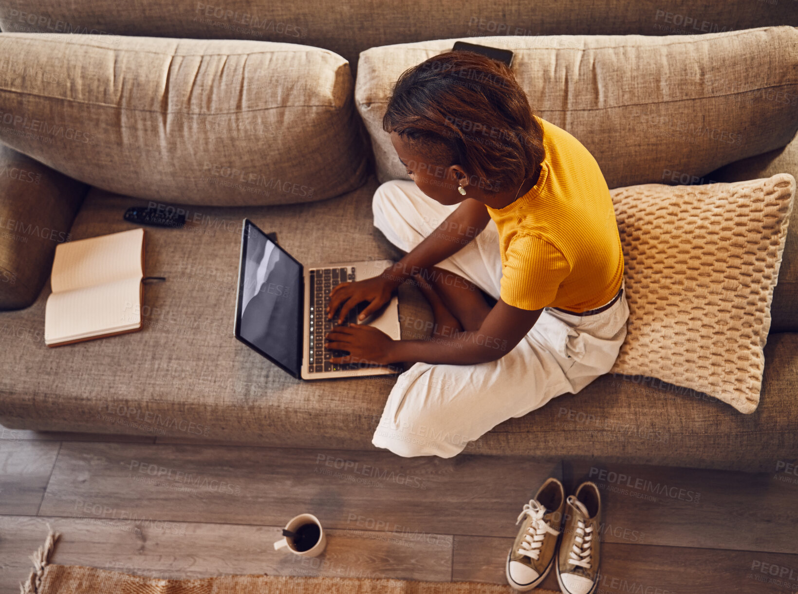 Buy stock photo Distance learning student writing, studying and typing on a laptop doing a virtual assignment test on the sofa at home. Above view of one young female writer or language editor typing an essay online