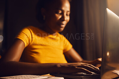 Young, happy and beautiful woman working on a laptop remotely while typing and answering emails. Smiling, positive black female completing a project late at night while sitting at a desk at home