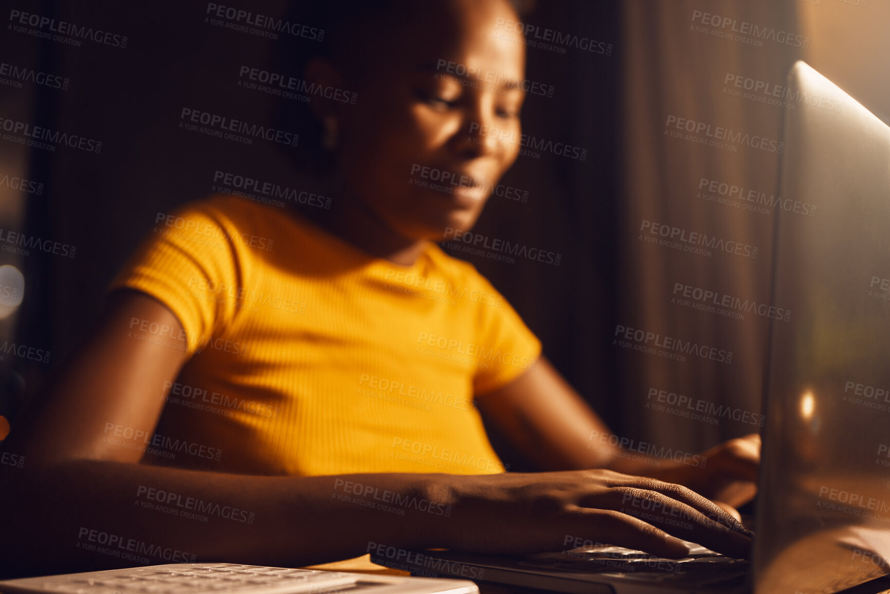 Buy stock photo Woman freelancer working remote on a laptop while typing and answering emails online. Smiling, positive black female entrepreneur completing a project late at night while sitting at a desk at home