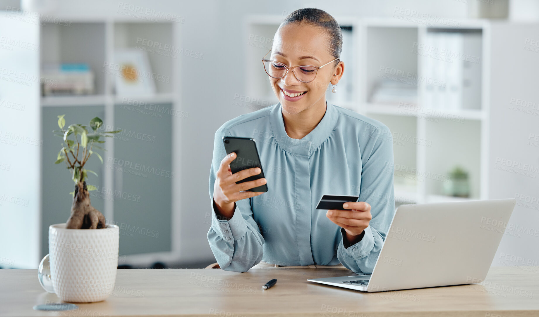 Buy stock photo Female executive online shopping, buying with a corporate credit card on a phone. A smiling woman paying business bills, sitting at office desk with laptop. Happy lady making a purchase on a website.