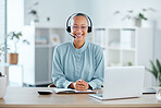 Happy and confident call center agent sitting in front of a laptop while wearing a headset in an office. Portrait of a happy saleswoman using web chat to assist customer sales and service support