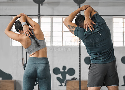 Active, sporty fitness couple or gym partners and friends training together, standing and doing arm stretching exercises. Back view of male trainer and female athlete warm up before workout class.