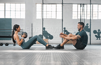 Active, sporty fitness couple or gym partners training together, doing abs exercises with a weighted slam ball. Male trainer and female athlete having a fun workout session or class.