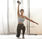 Training, fitness and active young woman doing exercise workout at an indoor gym for healthy lifestyle. Strong, focused and athletic female in sportswear half kneeling with one arm lifting dumbbell 