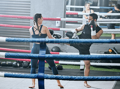 Fit, healthy and active woman doing fitness workout in the gym training to fight and kick box with her personal trainer at a wellness center. Athletic man and woman having boxing sports match in ring
