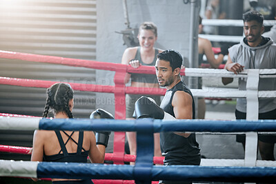 Buy stock photo Two young professional boxers preparing to fight and improve their skills in the boxing ring. Strong and focused athletes training together in the gym with friends watching from the sidelines.