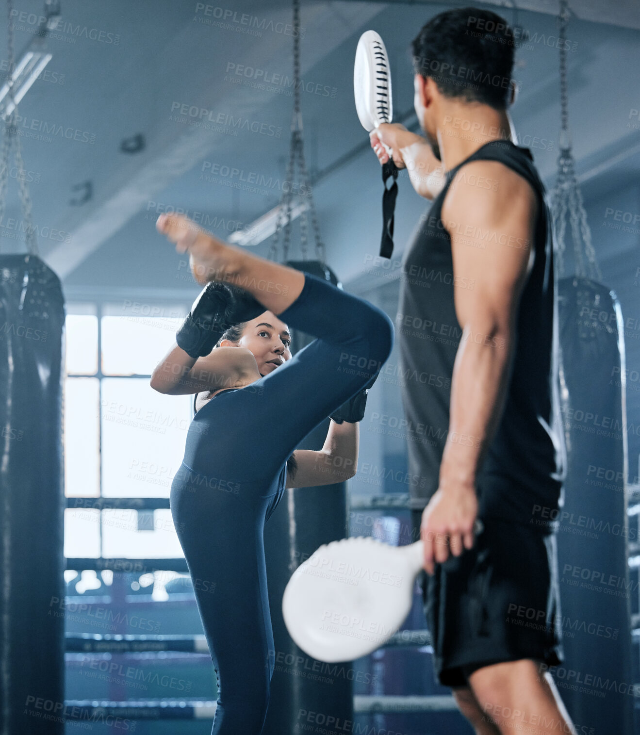 Buy stock photo Kickboxing, combat and fighter woman training high kicks with her coach in the gym. Female athlete performing martial arts and training, exercising or doing a workout for a fight with her trainer